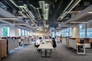 Three people at a desk in a large open office space